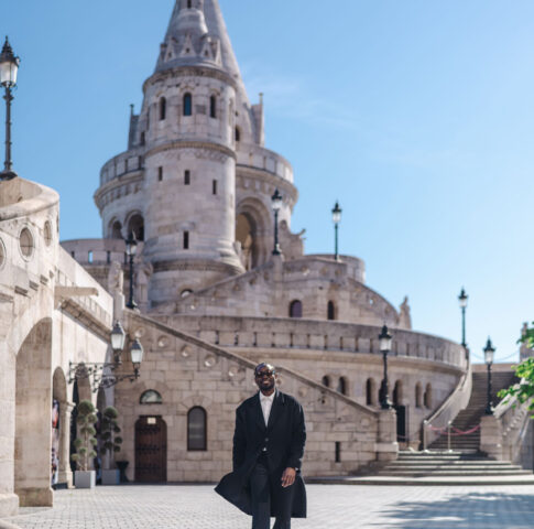 Man in elegant black coat walking down the steps of Fisherman's Bastion in Budapest on a sunny day